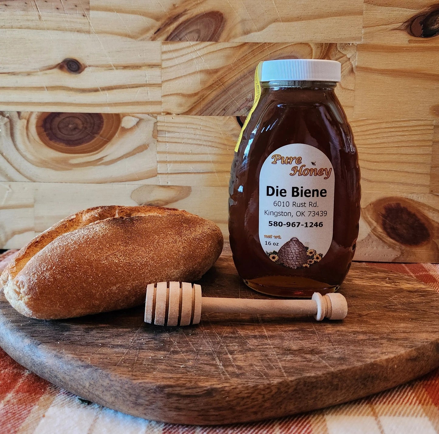 Bottle of Die Biene honey with a honey dipper on a wooden surface