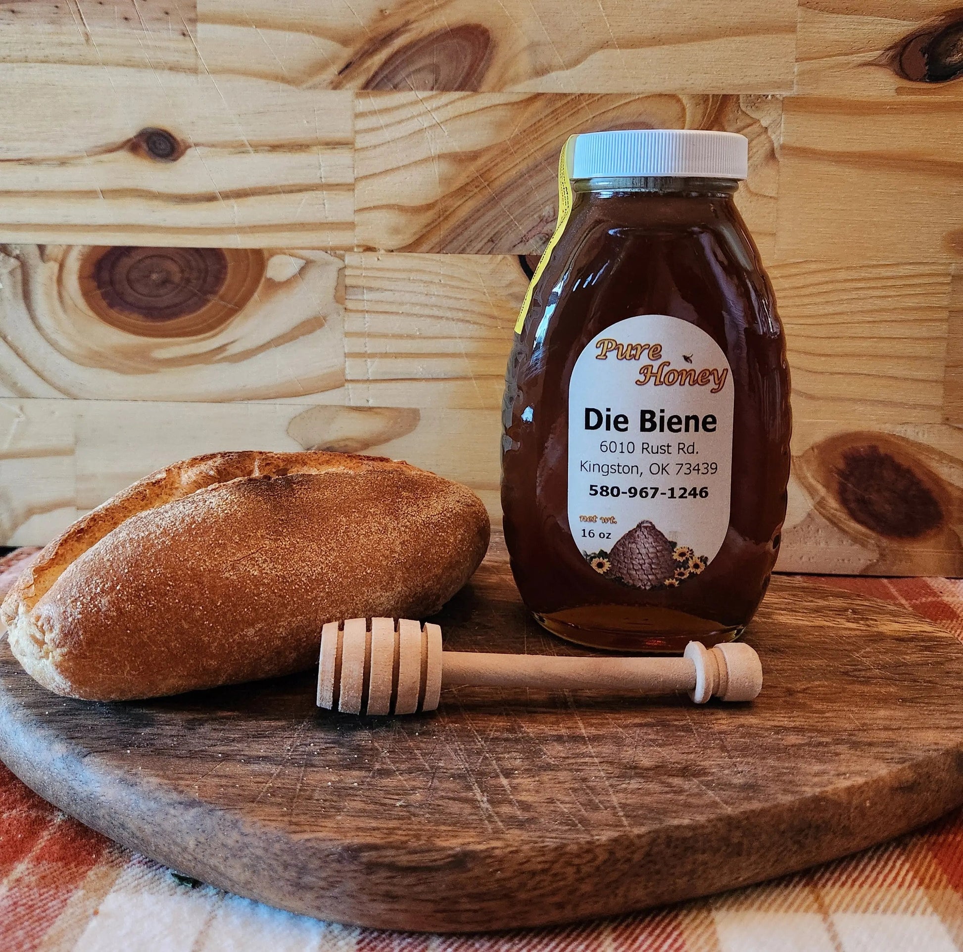 Bottle of Die Biene honey with a honey dipper on a wooden surface